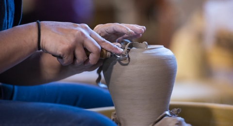 a persons legs and hands working on a ceramics peice